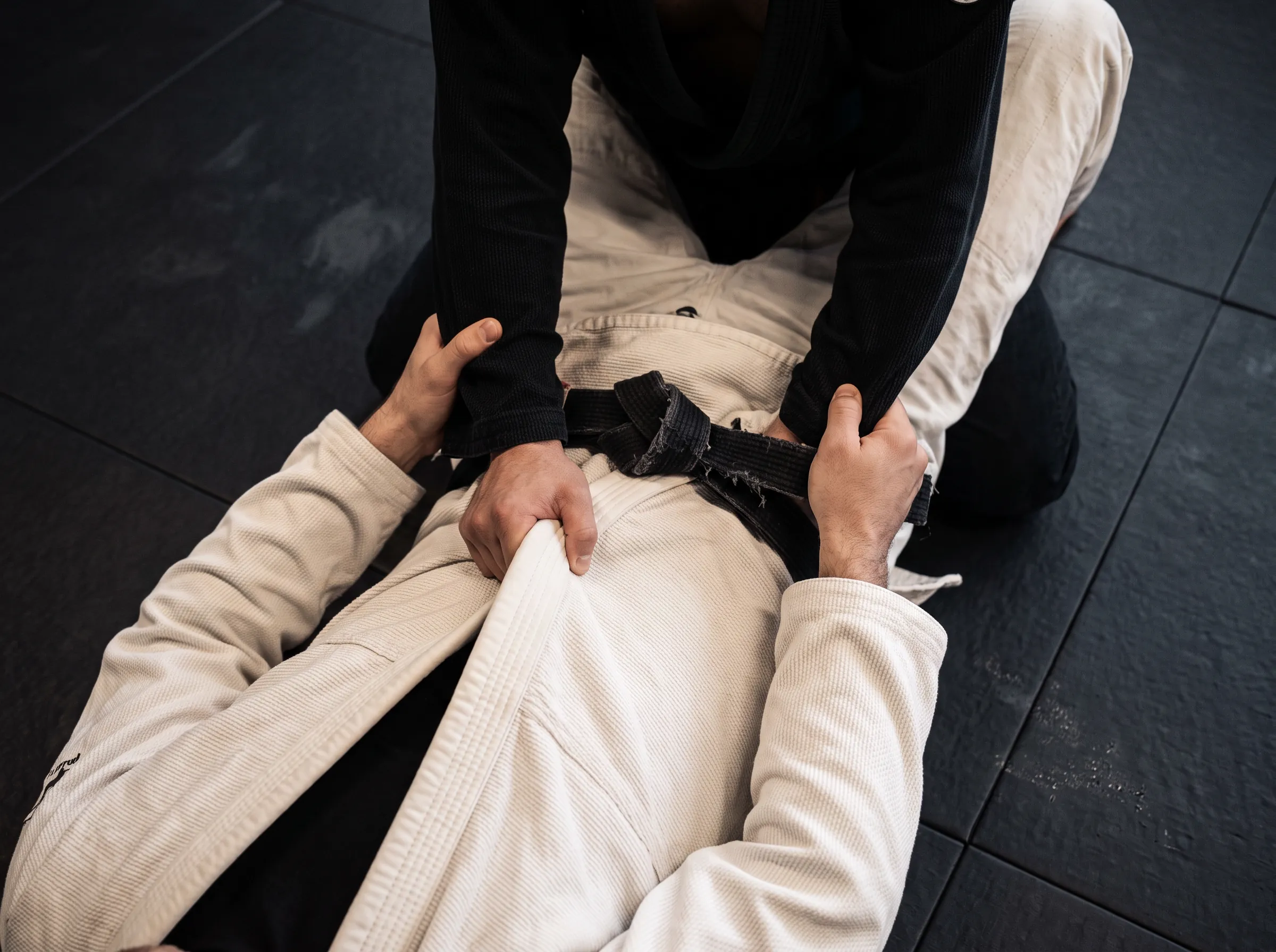 Griffe am Gürtel bei einer Jiu-Jitsu-Übung auf der Matte